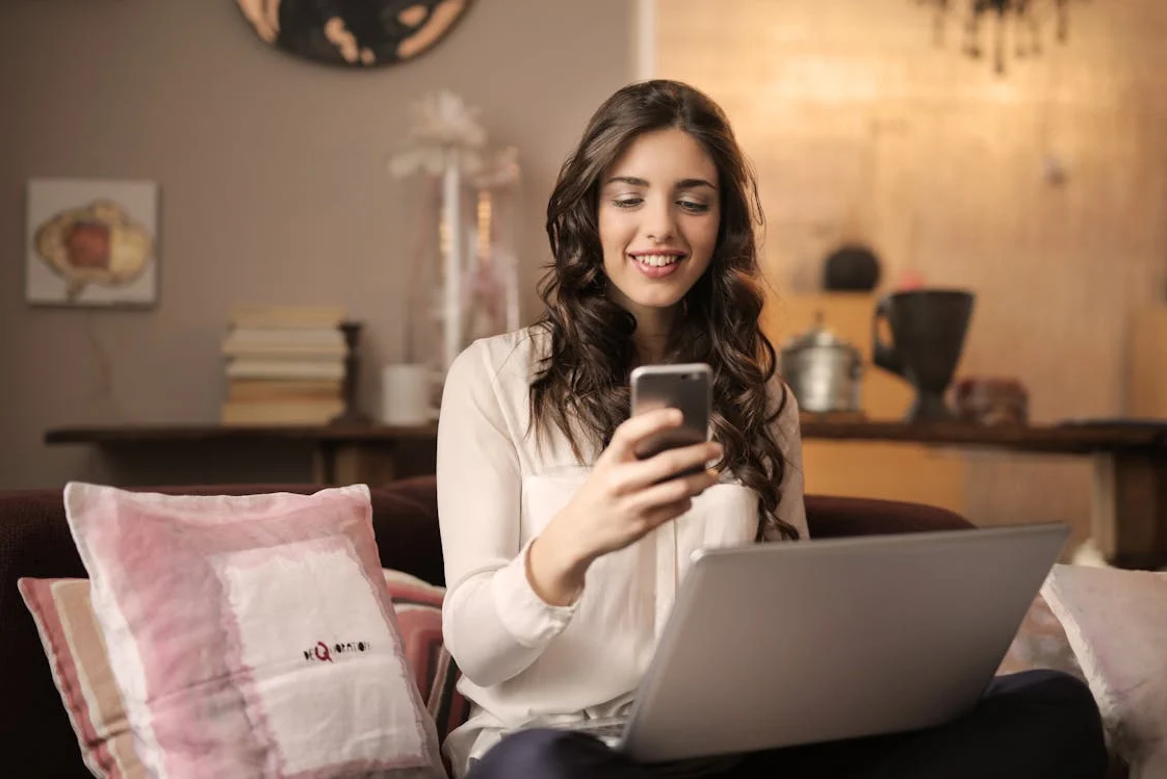 Woman with a laptop watching a smartphone