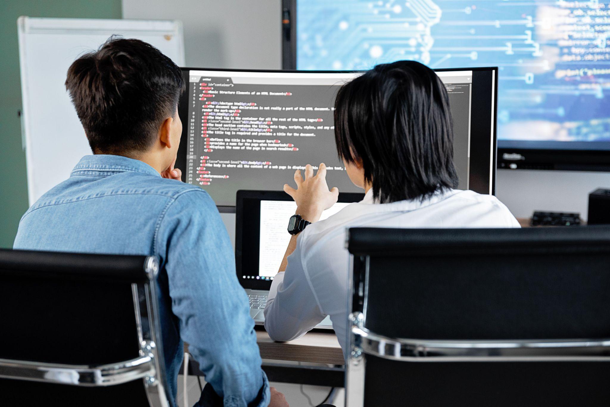 Developers discussing code at a computer.